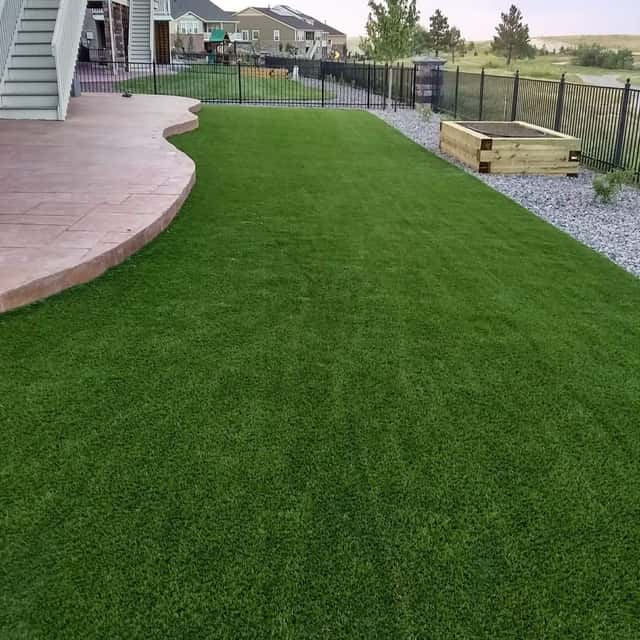 Synthetic turf lawn beside a stamped concrete patio under a deck — Angel's Landscaping LLC, Castle Rock, CO