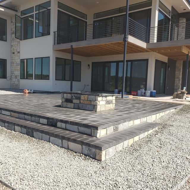Raised paver patio with seat wall and steps behind a modern home — Angel's Landscaping LLC, Castle Rock, CO