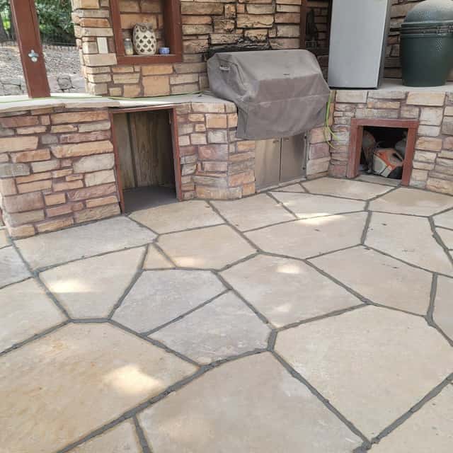 Flagstone patio in front of a stone outdoor kitchen with built-in grill — Angel's Landscaping LLC, Castle Rock, CO