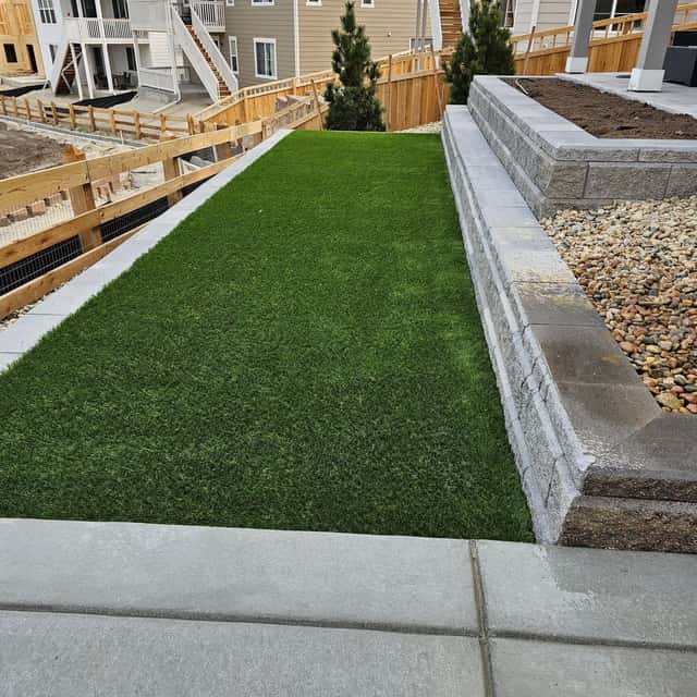 Synthetic turf strip between block retaining walls and a concrete pad — Angel's Landscaping LLC, Castle Rock, CO