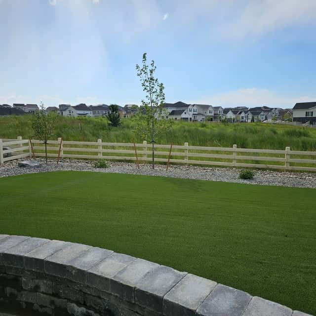Synthetic turf lawn edged by a low block wall and split-rail fence — Angel's Landscaping LLC, Castle Rock, CO